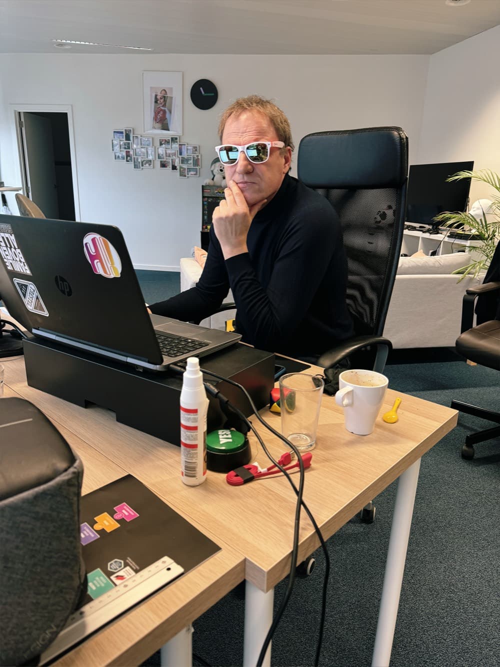 A team member at his desk, white sunglasses on.